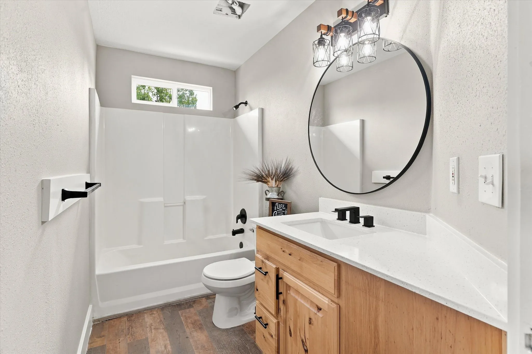 Bathroom featuring wood-finish flooring, a white vanity with a rectangular sink, a white countertop, and matte black fixtures