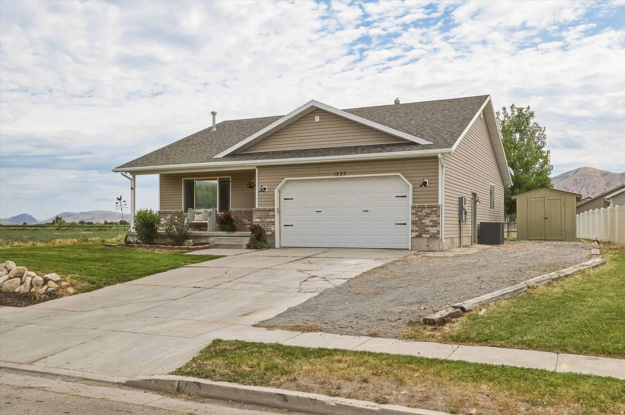 Ranch-style residence featuring a two-car garage, covered front porch, and a fenced side yard