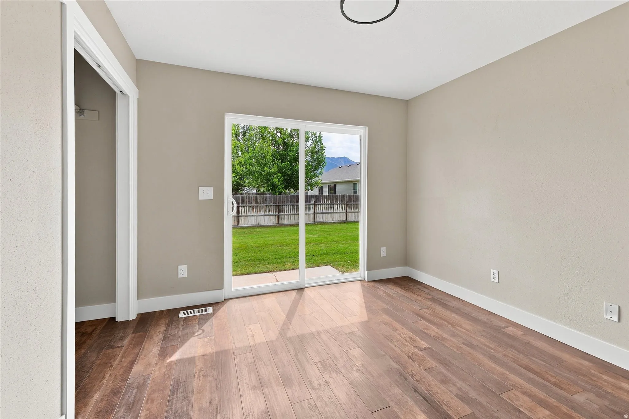 Room featuring wood-finish flooring, neutral wall paint, and white baseboards