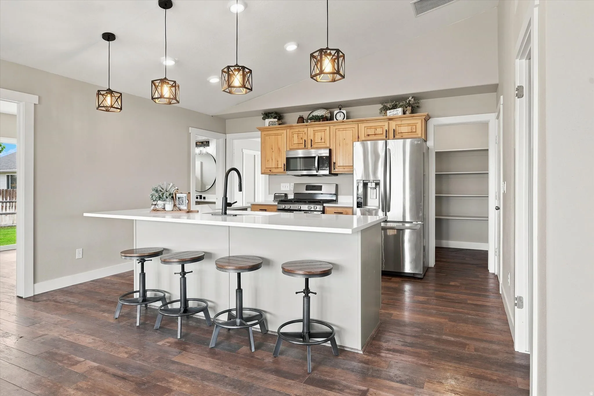 Kitchen featuring an island with white countertop, stainless steel appliances, wood-finish flooring, recessed lighting, and a pantry with built-in shelving
