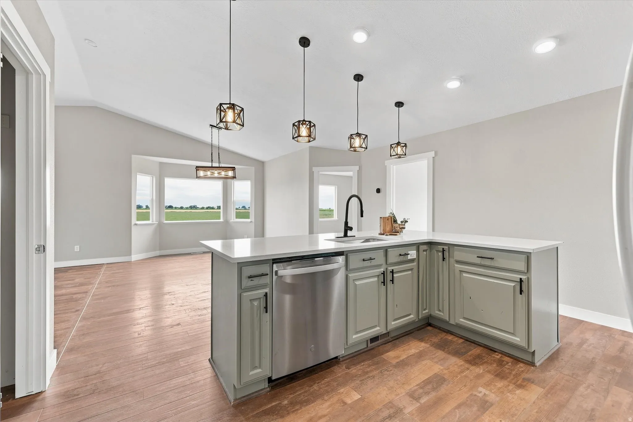 Kitchen island with light grey cabinetry, white countertop, and integrated stainless steel dishwasher