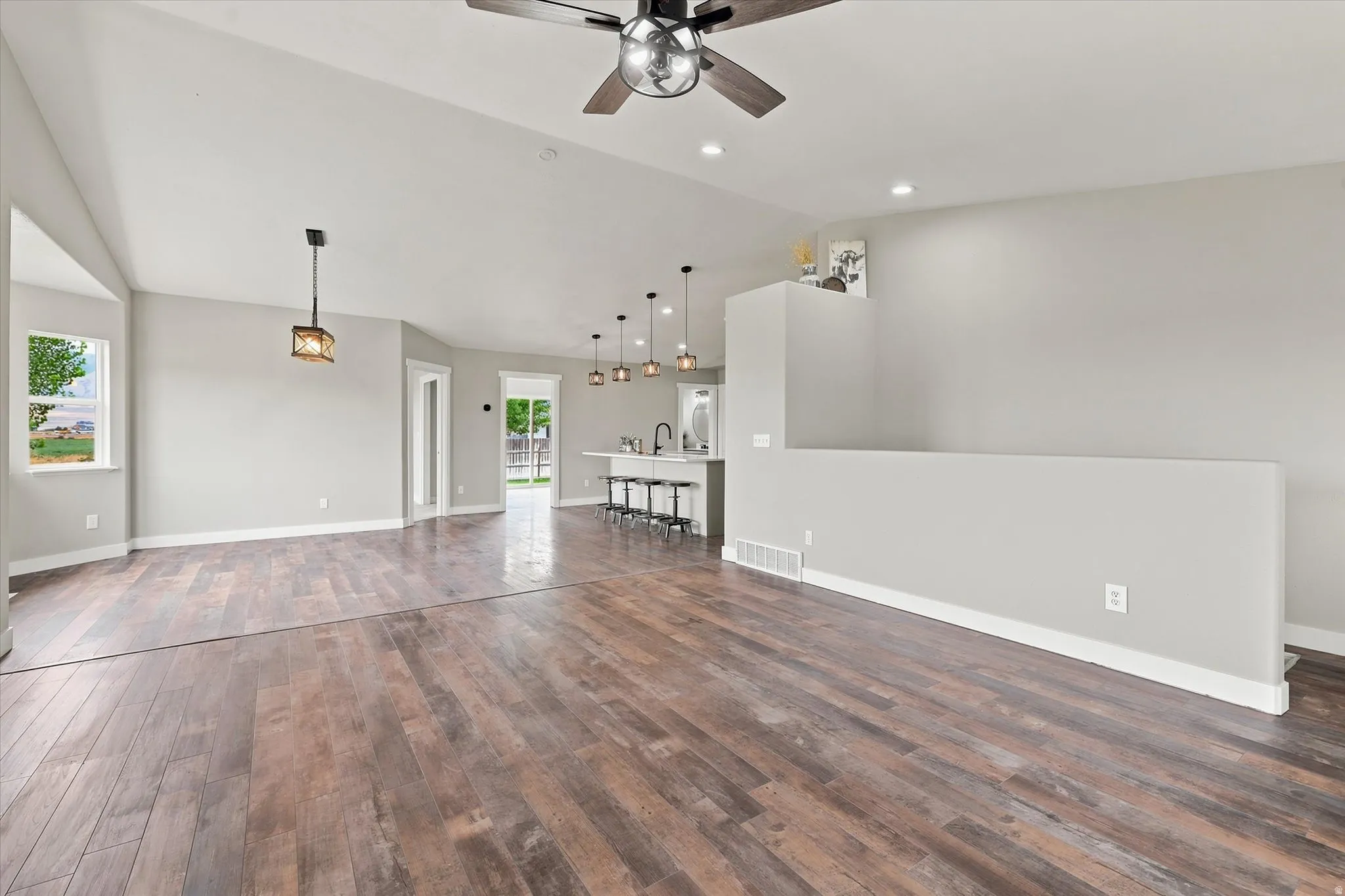 Spacious living area featuring wood-finish flooring, vaulted ceilings, and recessed lighting