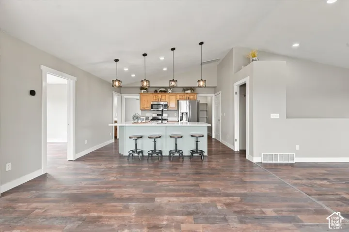 Spacious living area featuring wood-finish flooring, vaulted ceilings, and recessed lighting