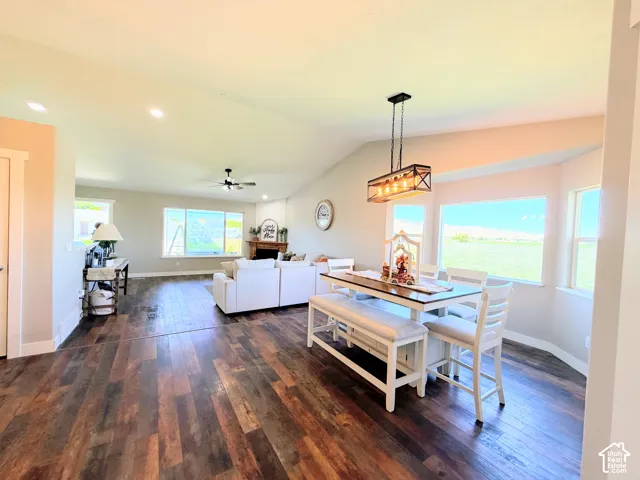 Vaulted ceilings, wood-finish flooring, a contemporary linear chandelier, recessed lighting, and a corner fireplace with a mantel