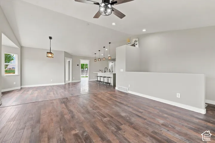 Spacious living area featuring wood-finish flooring, vaulted ceilings, and recessed lighting