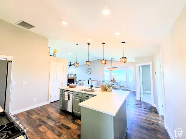 Wood-finish flooring, recessed lighting, kitchen island with built-in sink, stainless steel dishwasher, and pendant lighting