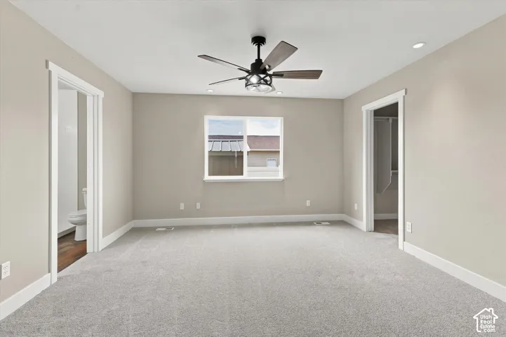 Spacious room with light neutral walls, gray carpet flooring, and white trim