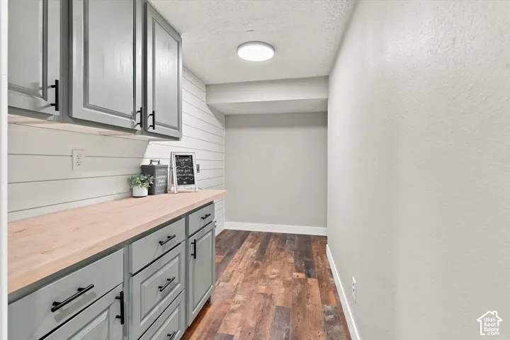 Extended countertop with custom cabinetry featuring matte black hardware, under-cabinet lighting, and shiplap-style backsplash