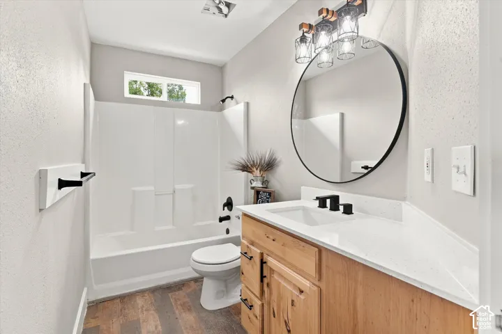Bathroom featuring wood-finish flooring, a white vanity with a rectangular sink, a white countertop, and matte black fixtures