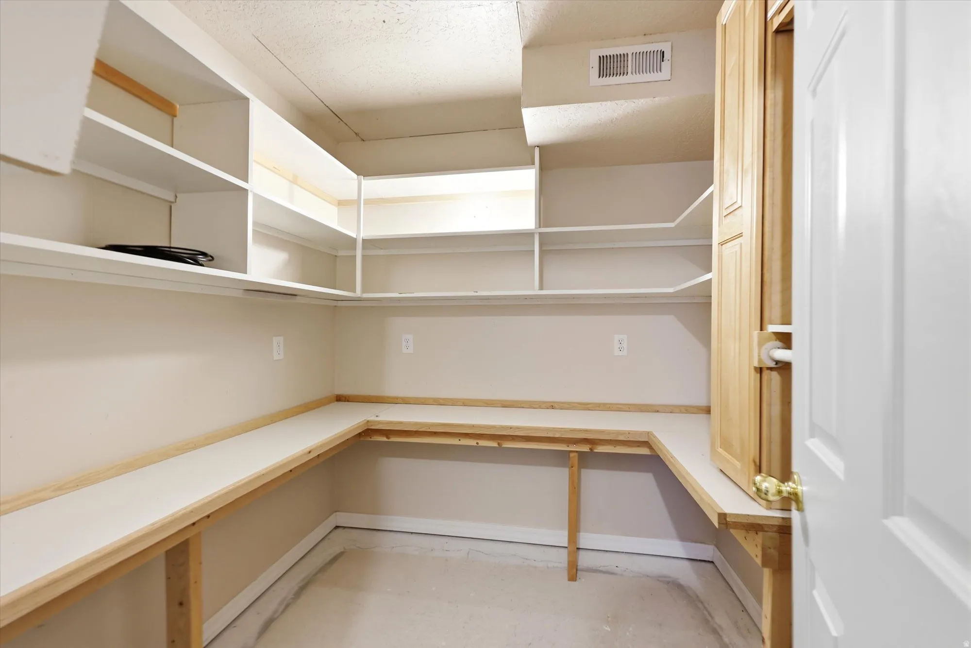 Second closet/room with built-in shelving, wrap-around countertop space, a cabinet, and hanging rod