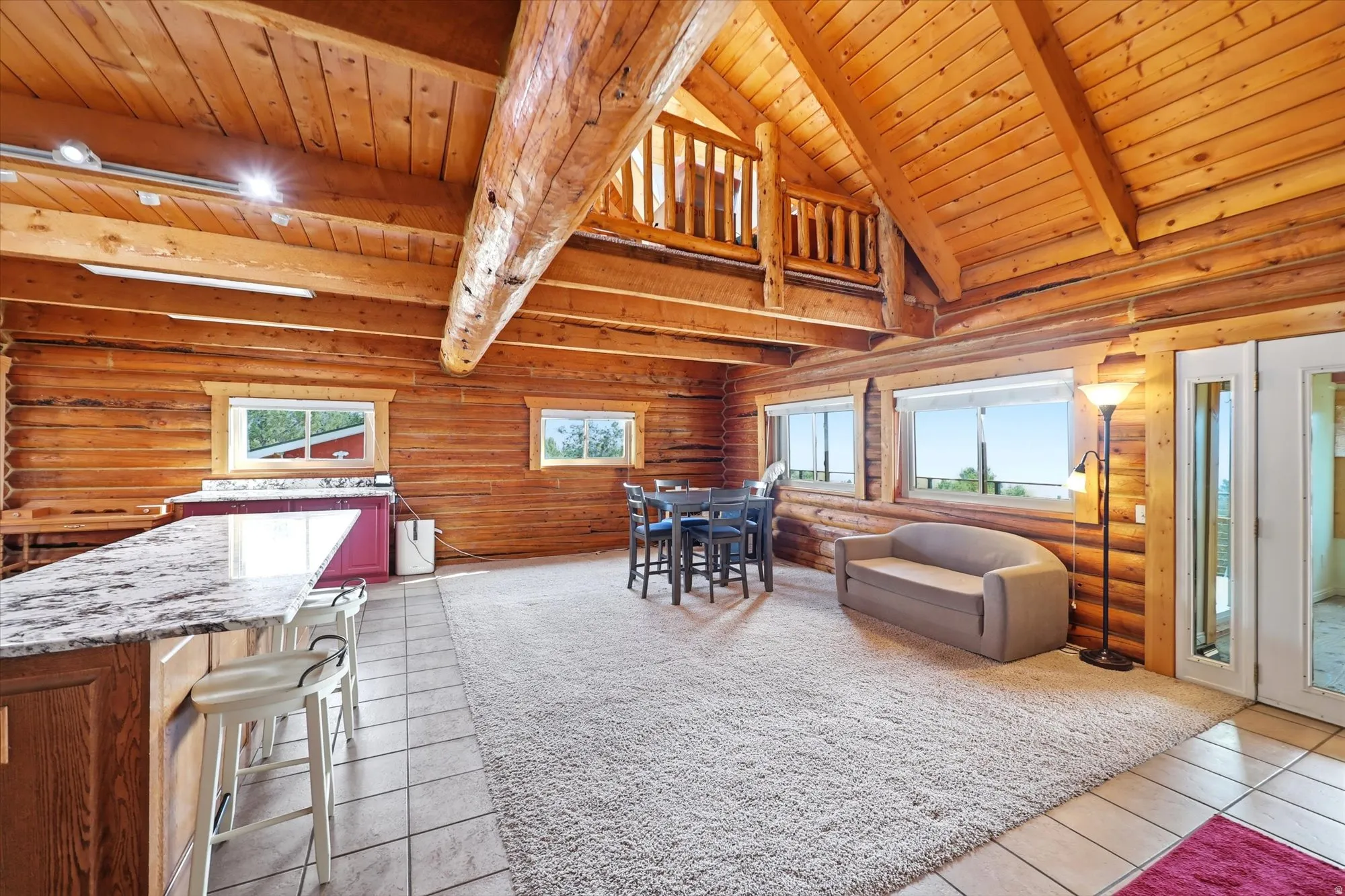 Great room featuring exposed log walls and beams, vaulted wood-paneled ceilings