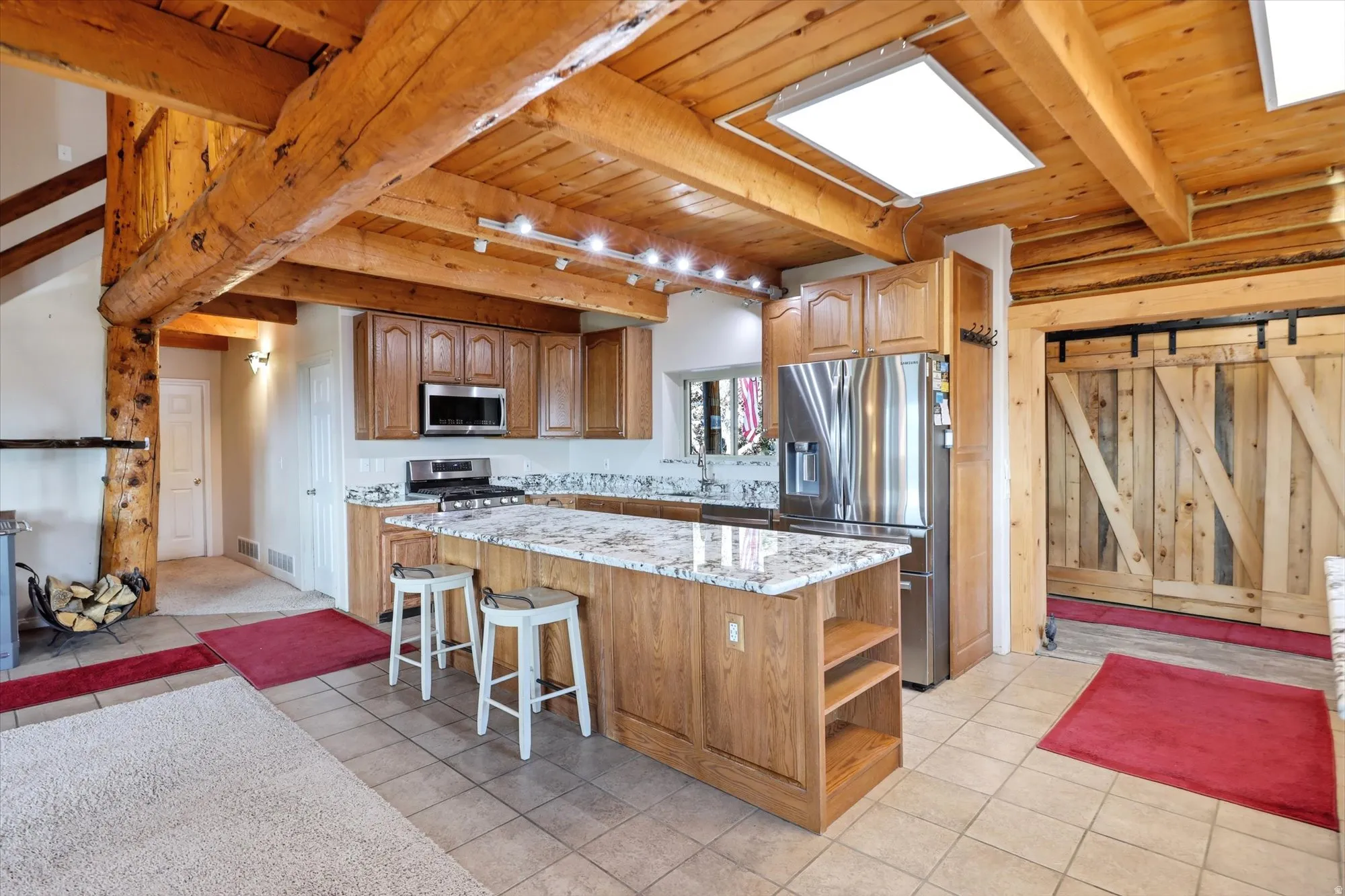 Kitchen featuring wood cabinetry, stainless steel appliances, a center island with bar seating, and granite countertops