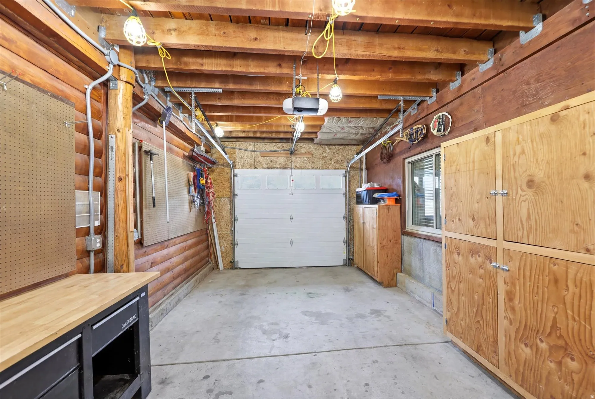Concrete floor garage/shop featuring wood-paneled walls, and a white garage door