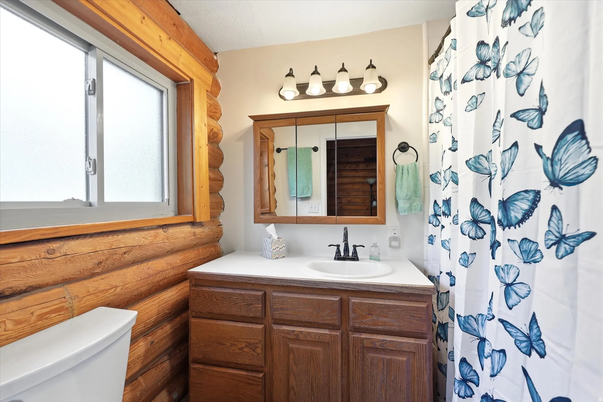 Bathroom featuring natural log walls, a frosted window and jetted tub