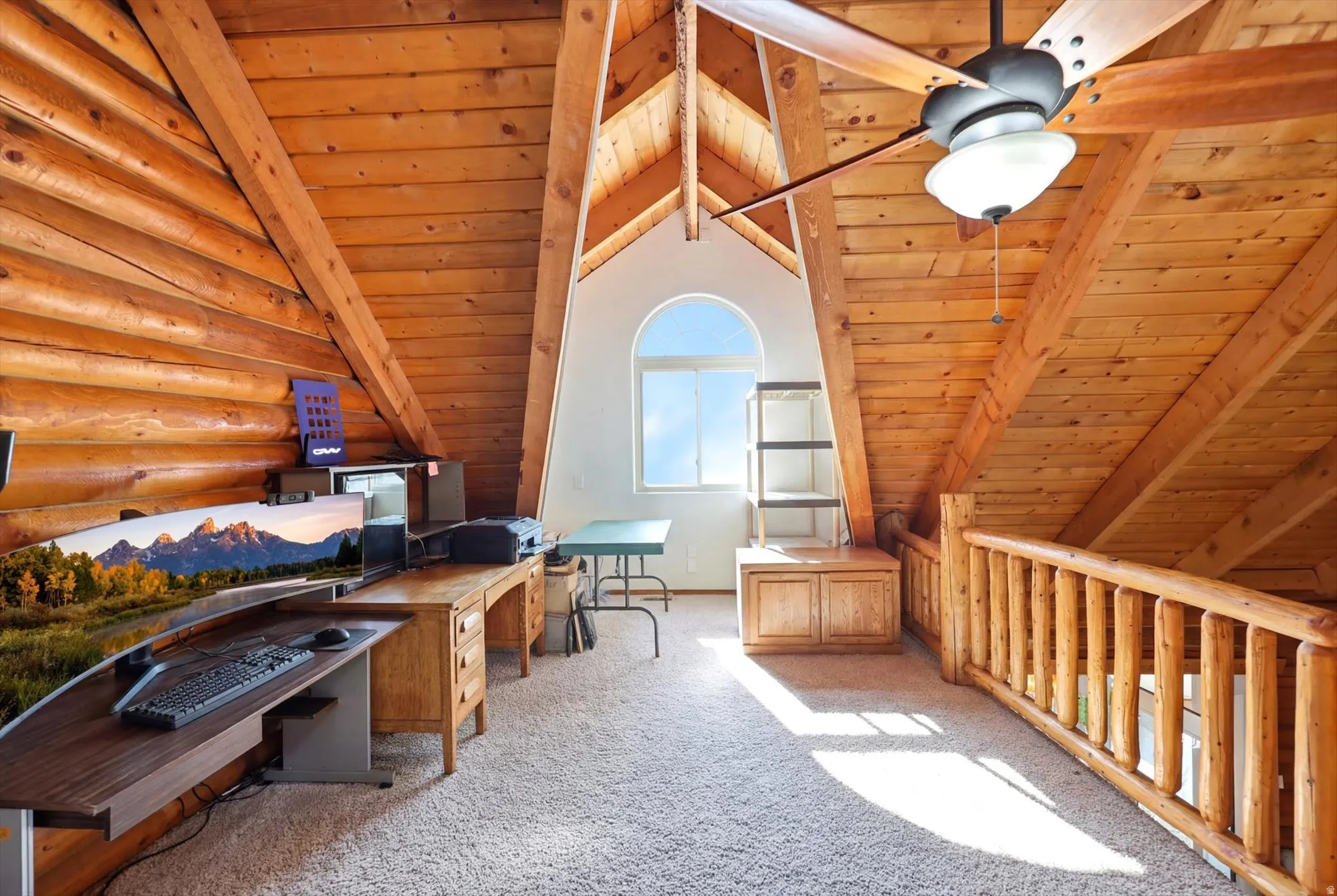 Loft space featuring extensive wood-finish walls and ceilings, a semi-circular window, and a wood baluster railing