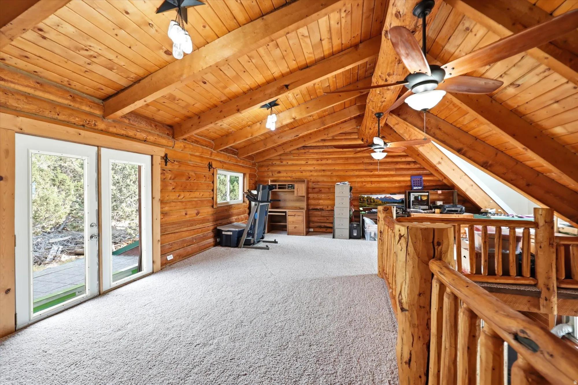 Vaulted wood-paneled ceilings with exposed beams, log walls, and light-colored carpeting