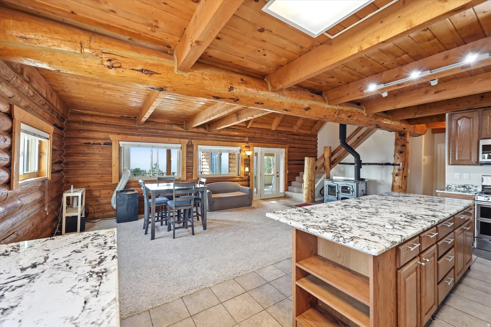 Open-concept living area featuring exposed wood beams and log walls