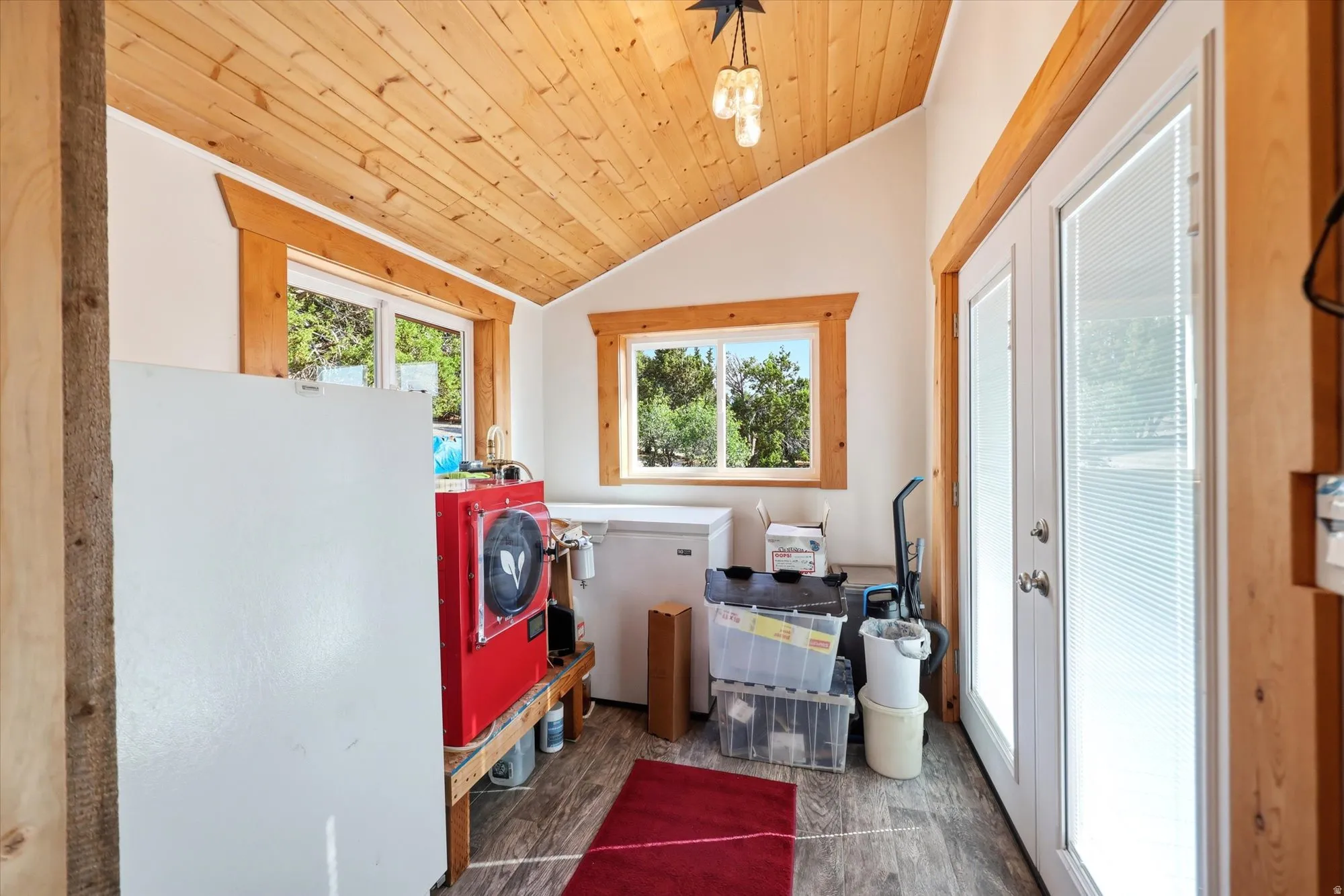 Sloped wood-finish plank ceiling with exposed beams, wood-finish window trim, and dual pane glass doors