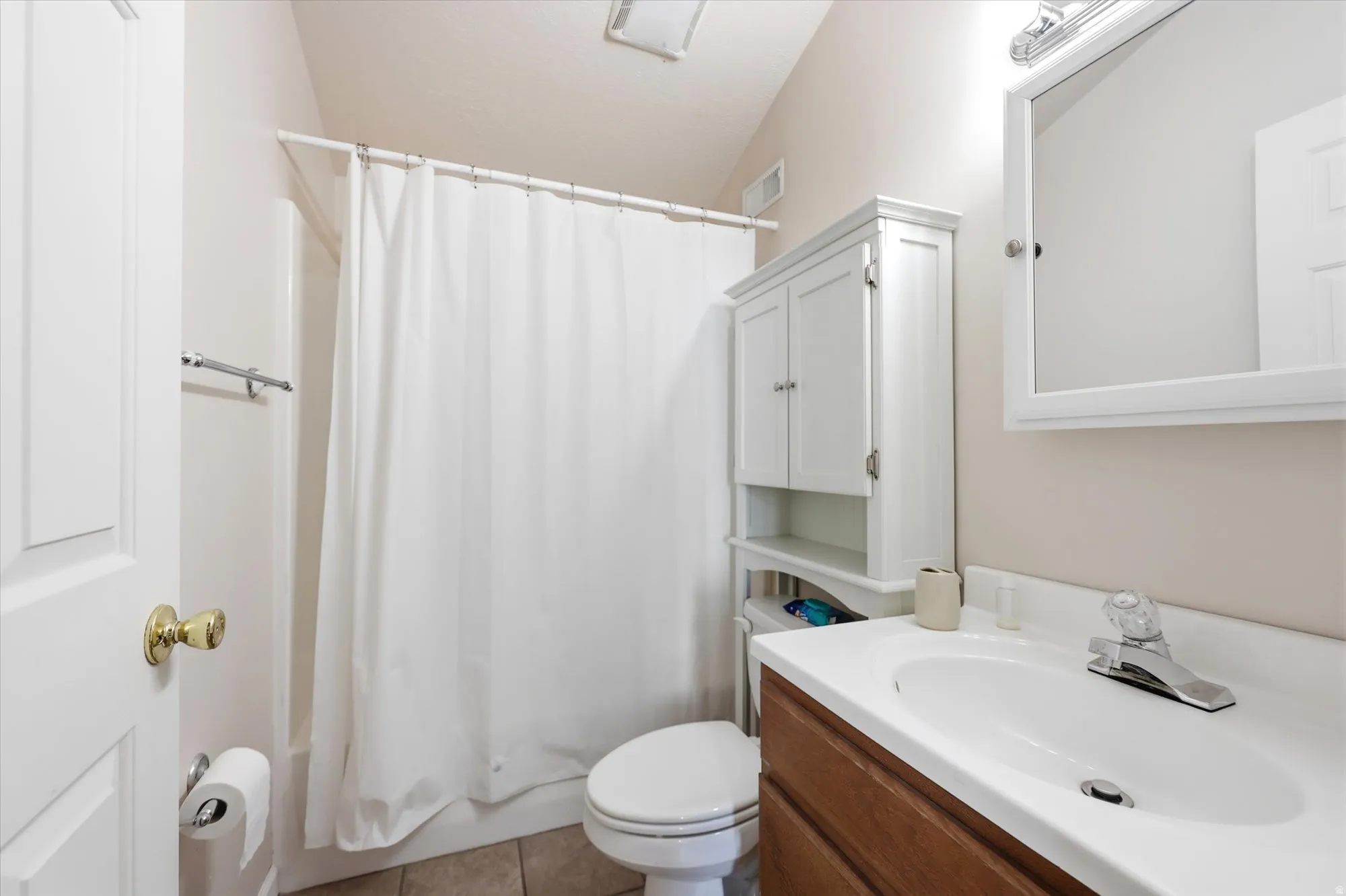 Bathroom featuring a wood-finish vanity with an integrated sink, white medicine cabinet, and a shower-tub combination