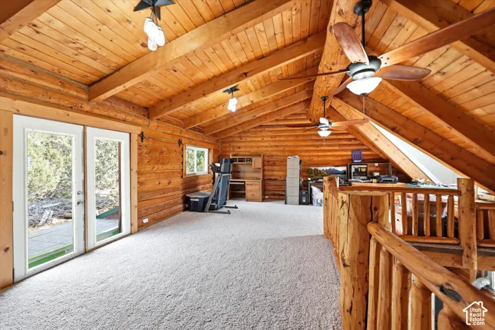Vaulted wood-paneled ceilings with exposed beams, log walls, and light-colored carpeting