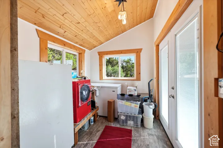 Sloped wood-finish plank ceiling with exposed beams, wood-finish window trim, and dual pane glass doors