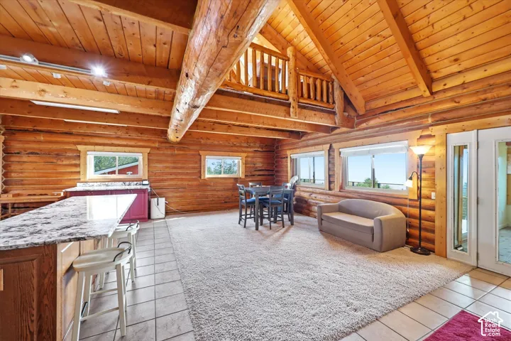 Great room featuring exposed log walls and beams, vaulted wood-paneled ceilings