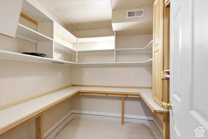 Second closet/room with built-in shelving, wrap-around countertop space, a cabinet, and hanging rod