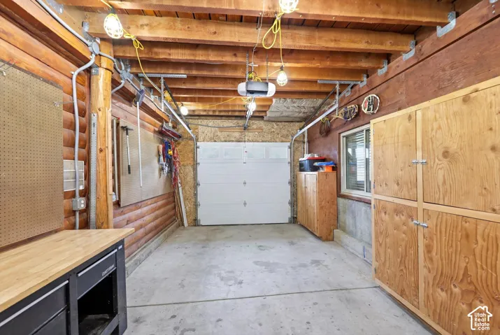 Concrete floor garage/shop featuring wood-paneled walls, and a white garage door
