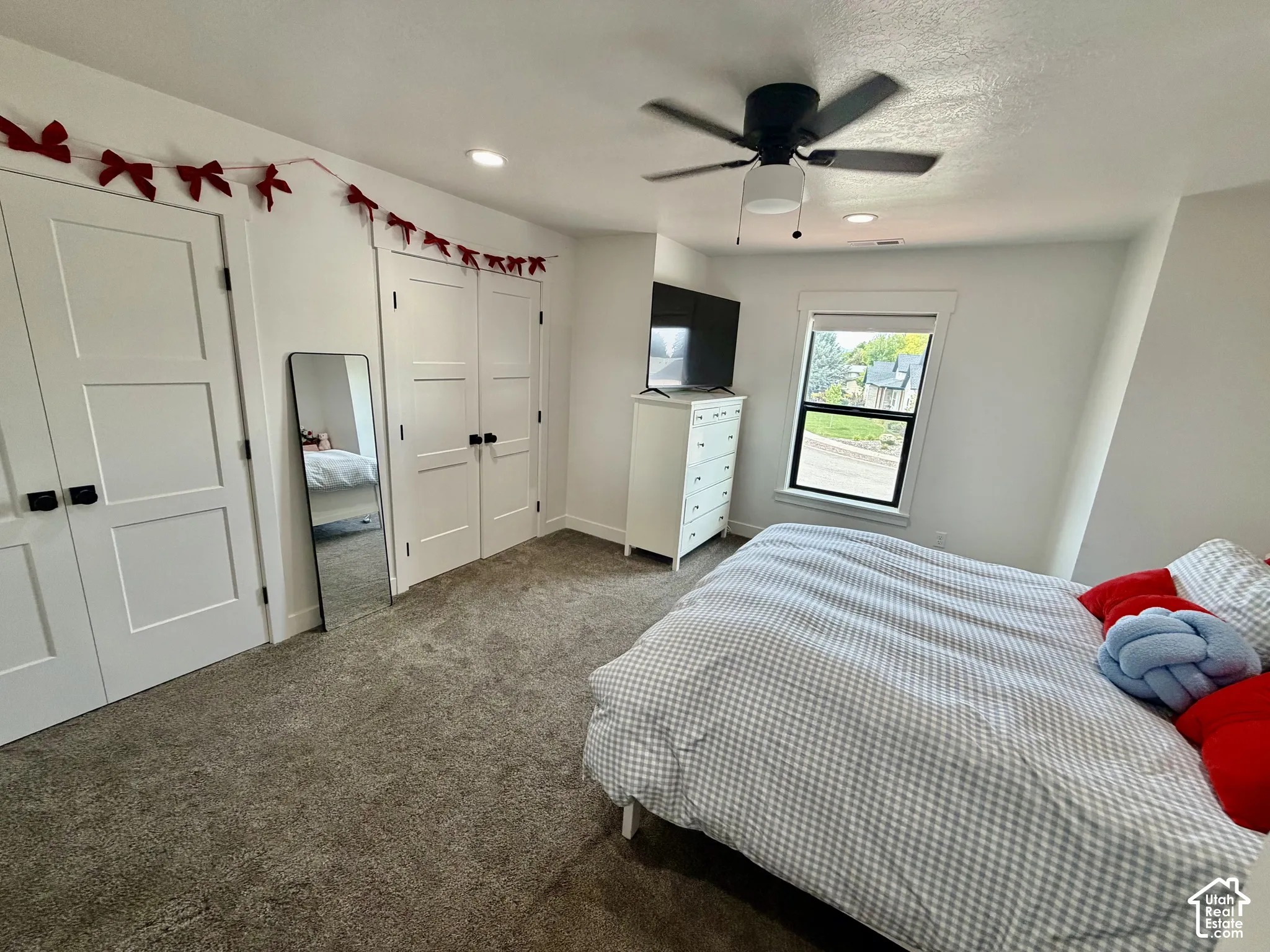 Bedroom featuring modern three-panel doors, neutral carpet flooring, and a contemporary ceiling fan with integrated lighting