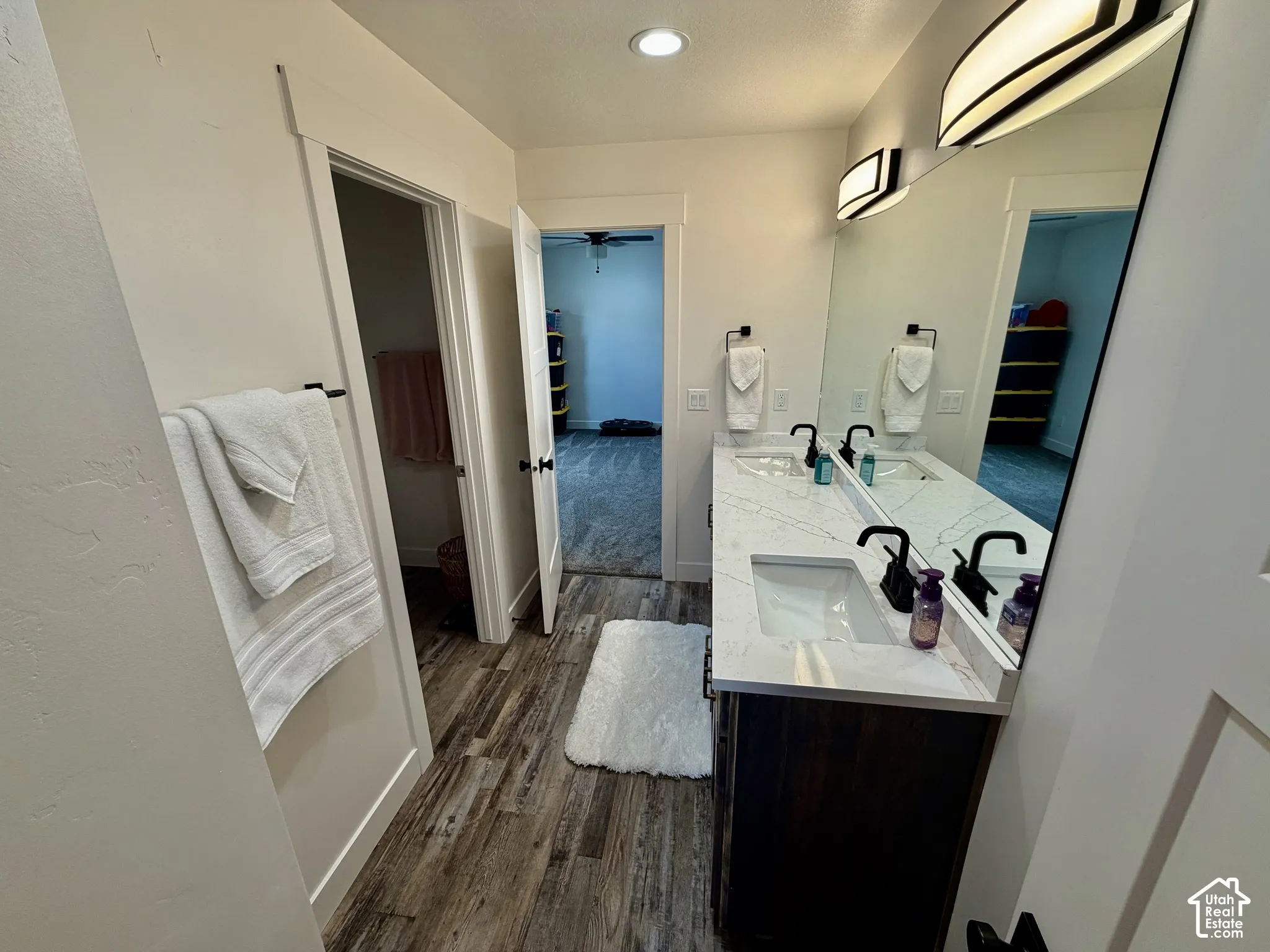 Dual vanity with undermount sinks and dark wood-finish cabinetry, illuminated by wall-mounted sconces