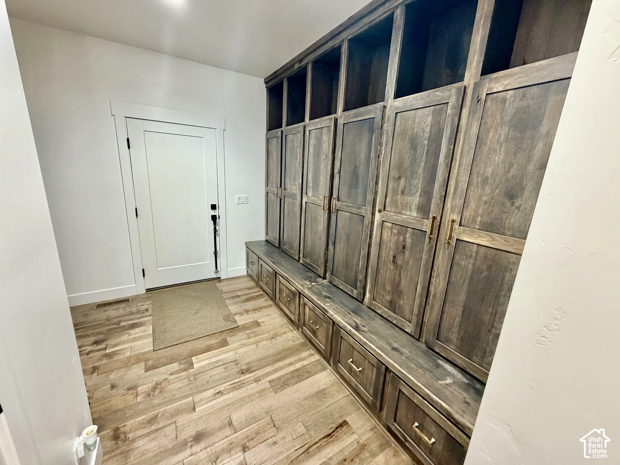 Built-in custom cabinetry featuring open shelving and closed storage, integrated bench seating, and wood-finish flooring