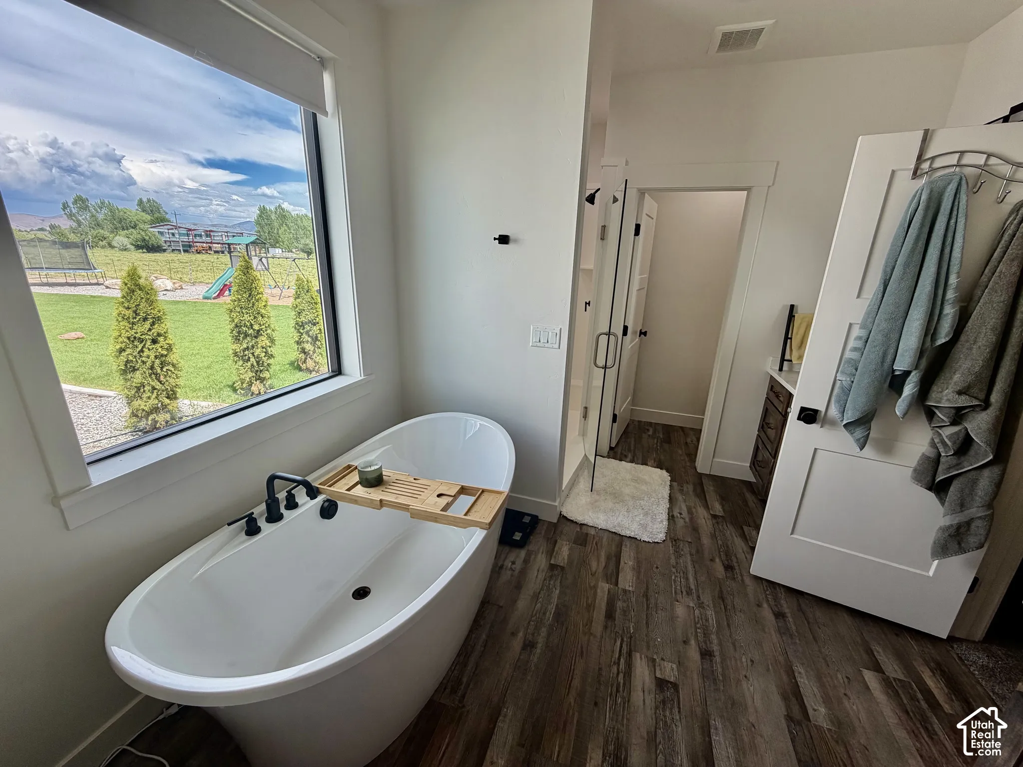 Freestanding soaking tub with matte black fixtures, set against a large window overlooking a landscaped yard