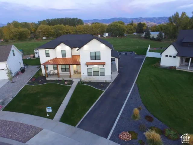 White exterior with black trim windows, covered front porch, copper-finish roof accents, and a paved driveway