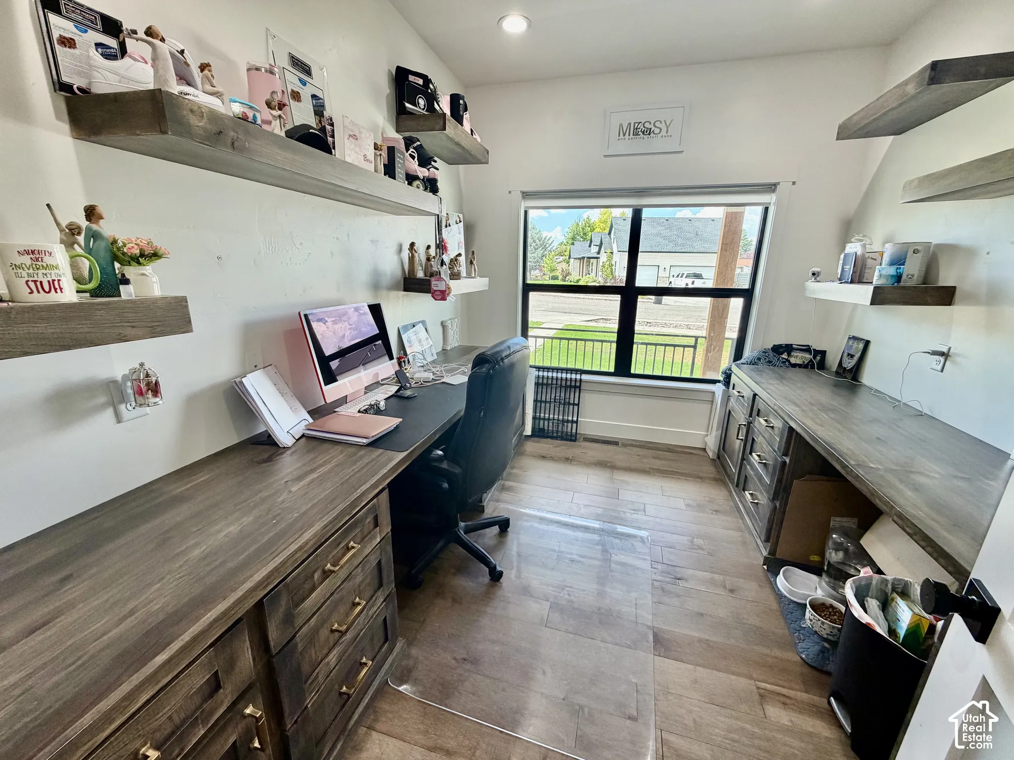 Dedicated workspace featuring extensive built-in cabinetry with wood-finish countertops, wood-finish flooring, and multiple floating shelves
