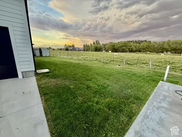Expansive green lawn with a bordering field and distant trees