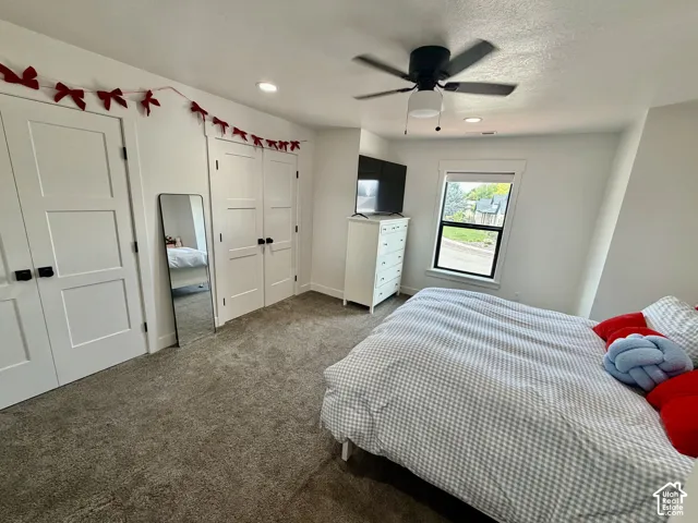 Bedroom featuring modern three-panel doors, neutral carpet flooring, and a contemporary ceiling fan with integrated lighting