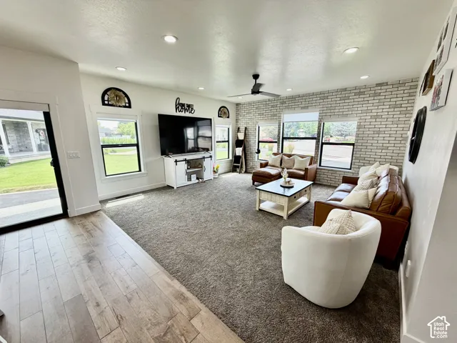 Spacious living area featuring a prominent white brick accent wall, recessed lighting, and a ceiling fan