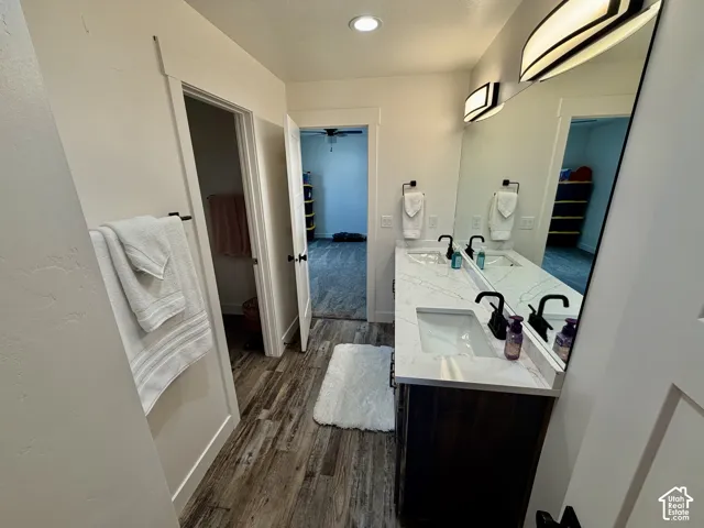 Dual vanity with undermount sinks and dark wood-finish cabinetry, illuminated by wall-mounted sconces