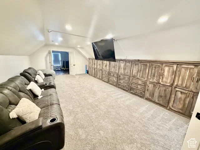 Spacious room featuring sloped ceilings, recessed lighting, and a wall of built-in cabinetry with a wood-finish