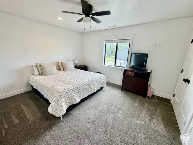 Carpeted bedroom with a ceiling fan, recessed lighting, and a window with white trim