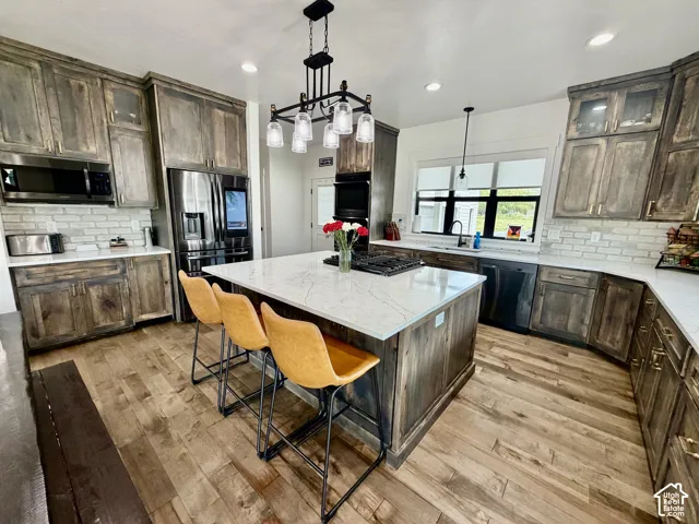 Open-concept kitchen featuring wood-finish flooring, a central island with a cooktop and seating, and extensive cabinetry