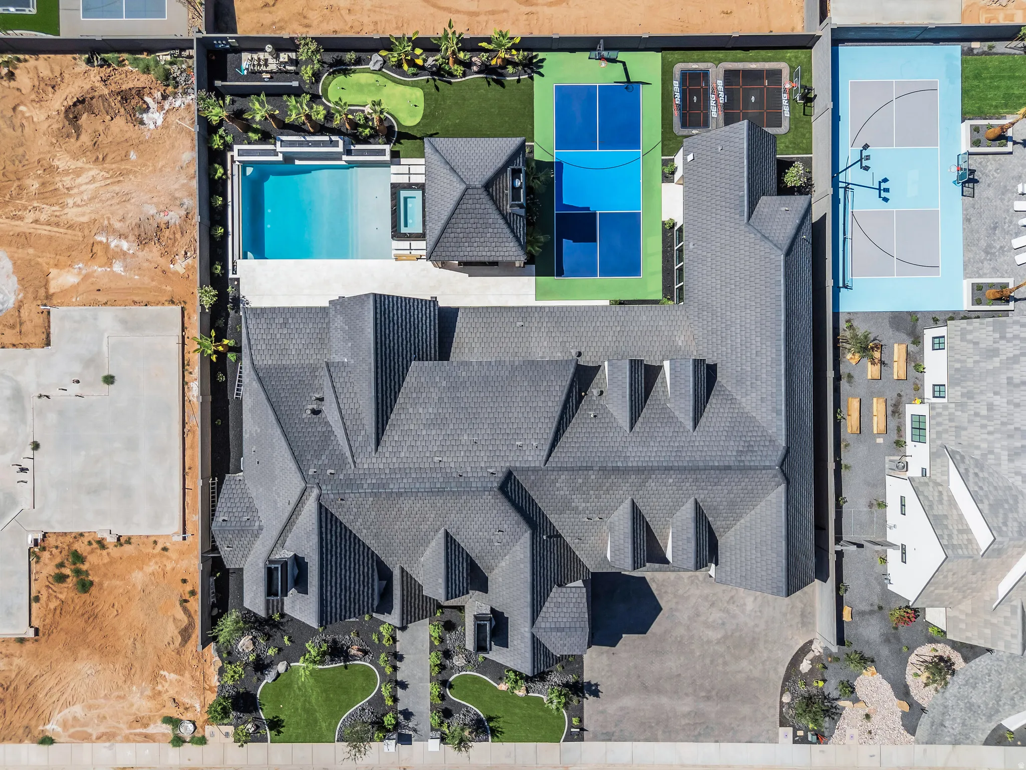 Extensive property featuring a multi-gabled roofline, a rectangular swimming pool with an integrated spa, a dedicated putting green, a sports court, and a separate full-size basketball court