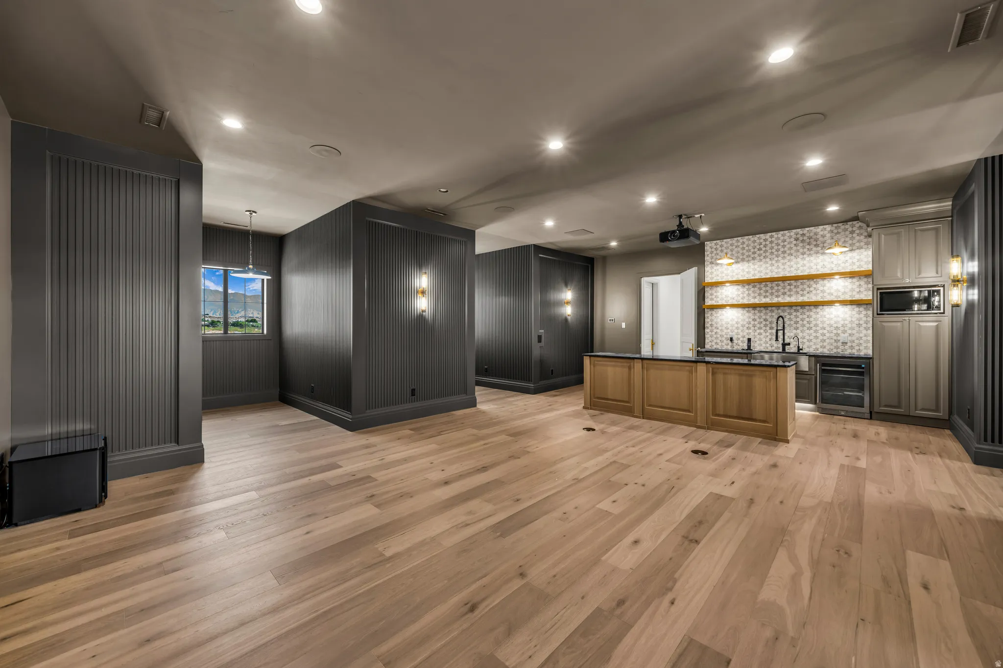 Spacious room featuring wood-finish flooring, recessed lighting, and dark gray accent walls with paneling