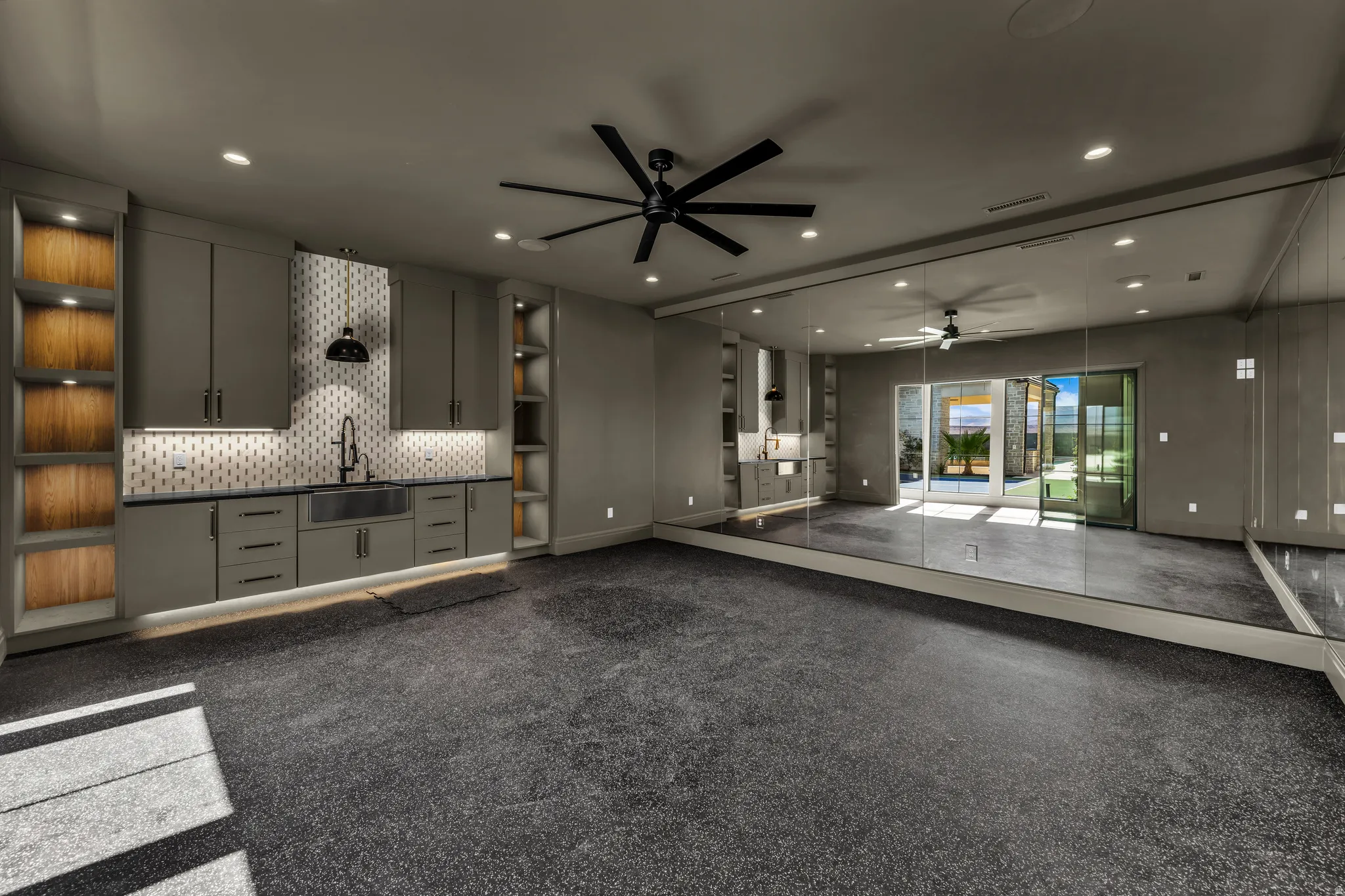 Spacious multi-purpose room featuring a built-in wet bar, full-height wall mirrors, recessed lighting, and a ceiling fan