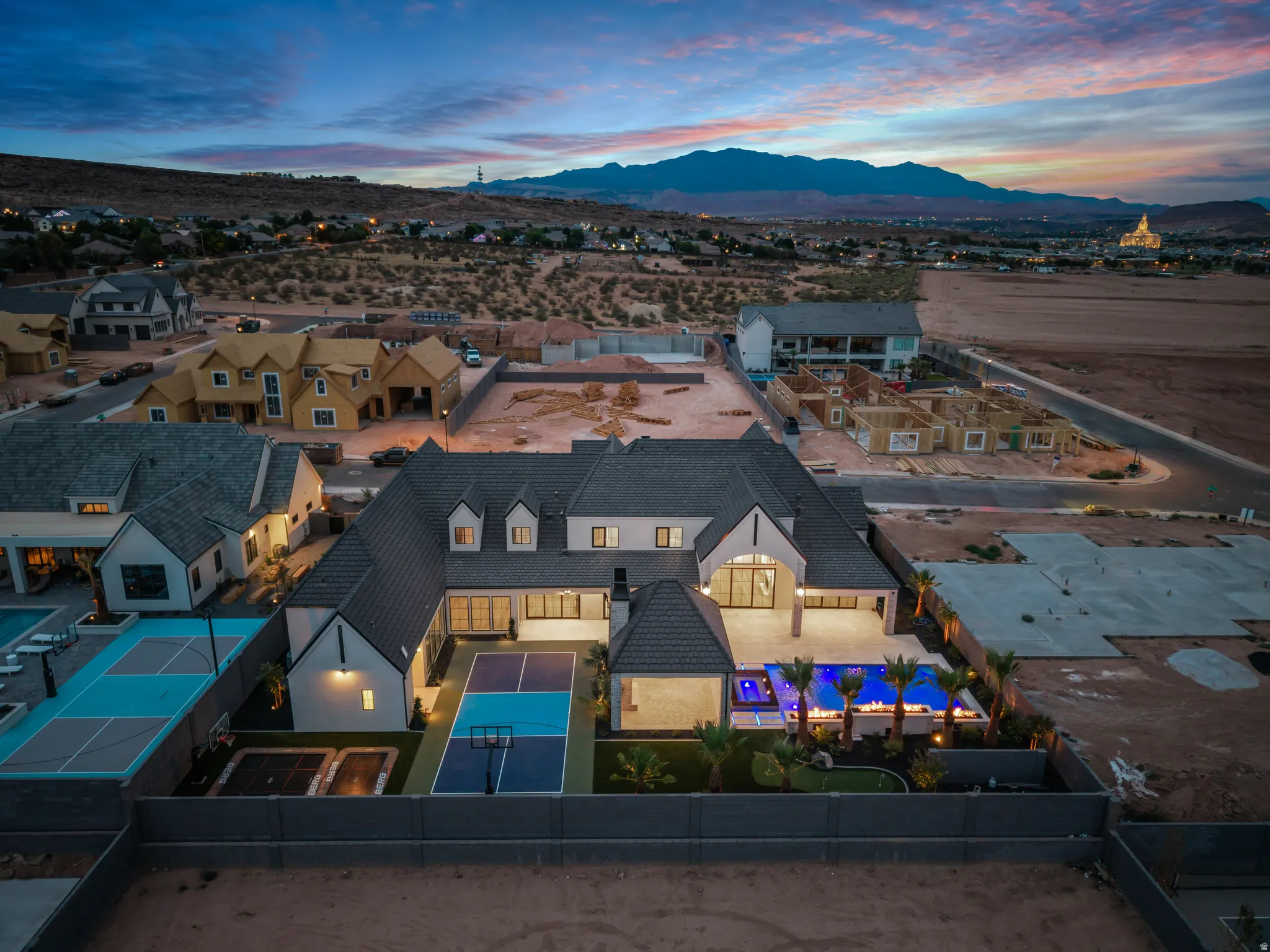 Modern residential compound featuring a large central dwelling, expansive multi-sport court, a putting green, and a contemporary swimming pool with integrated spa