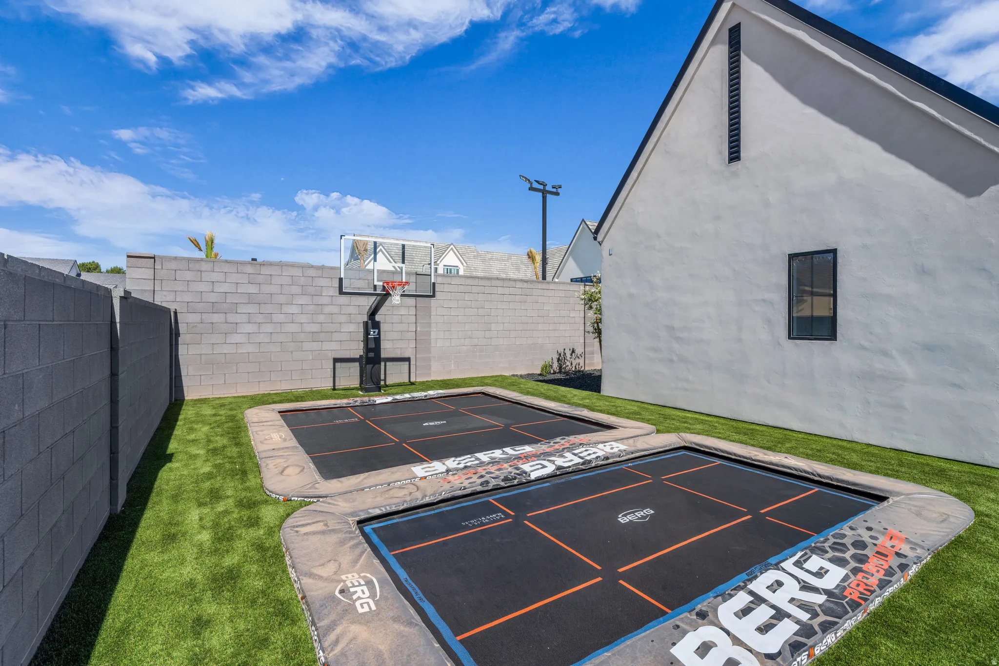Backyard featuring artificial turf, a masonry block perimeter wall, and a side elevation of the property with a single window