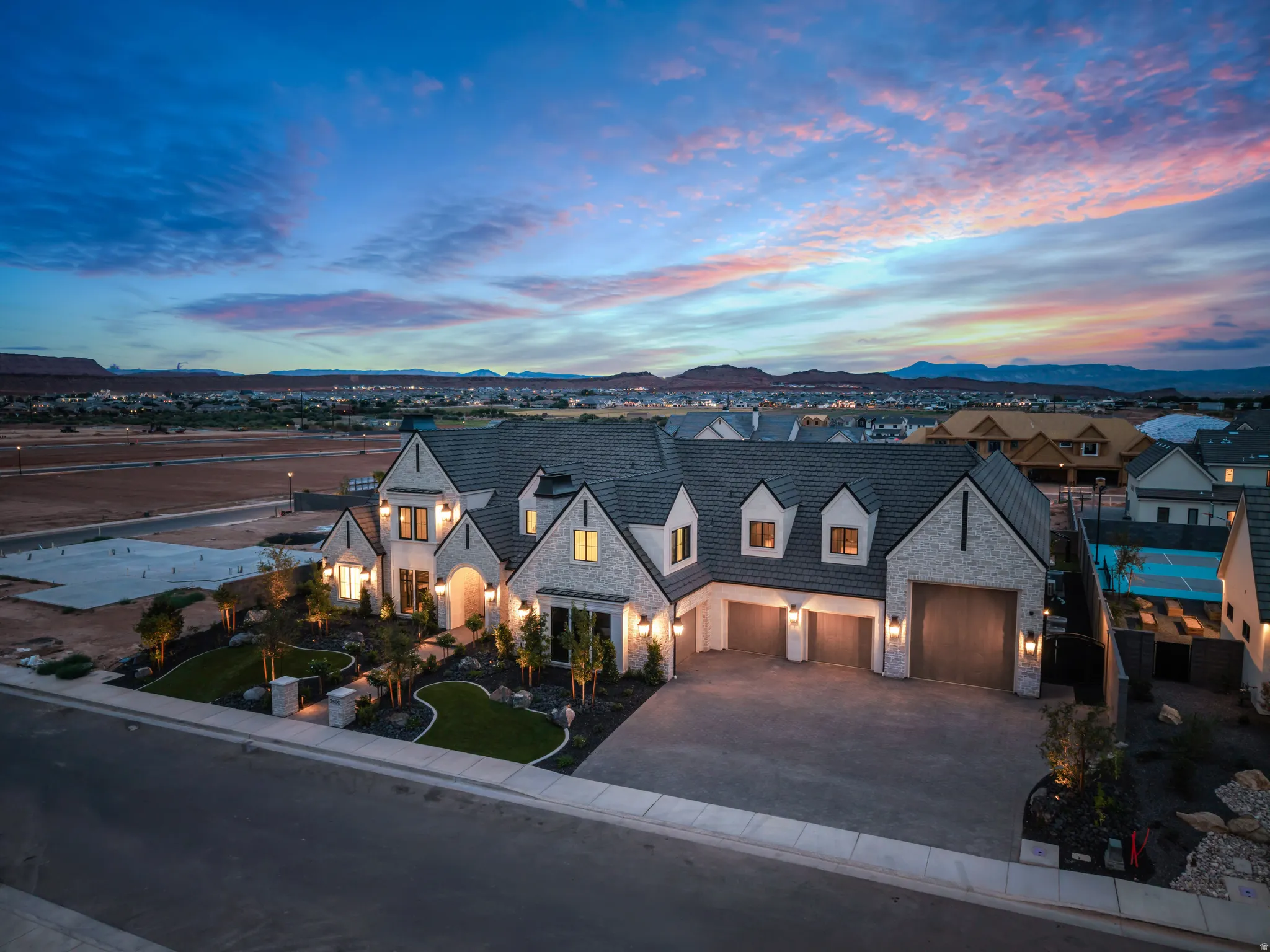 Architectural residence featuring a multi-gable roofline, stone facade, and a paver driveway