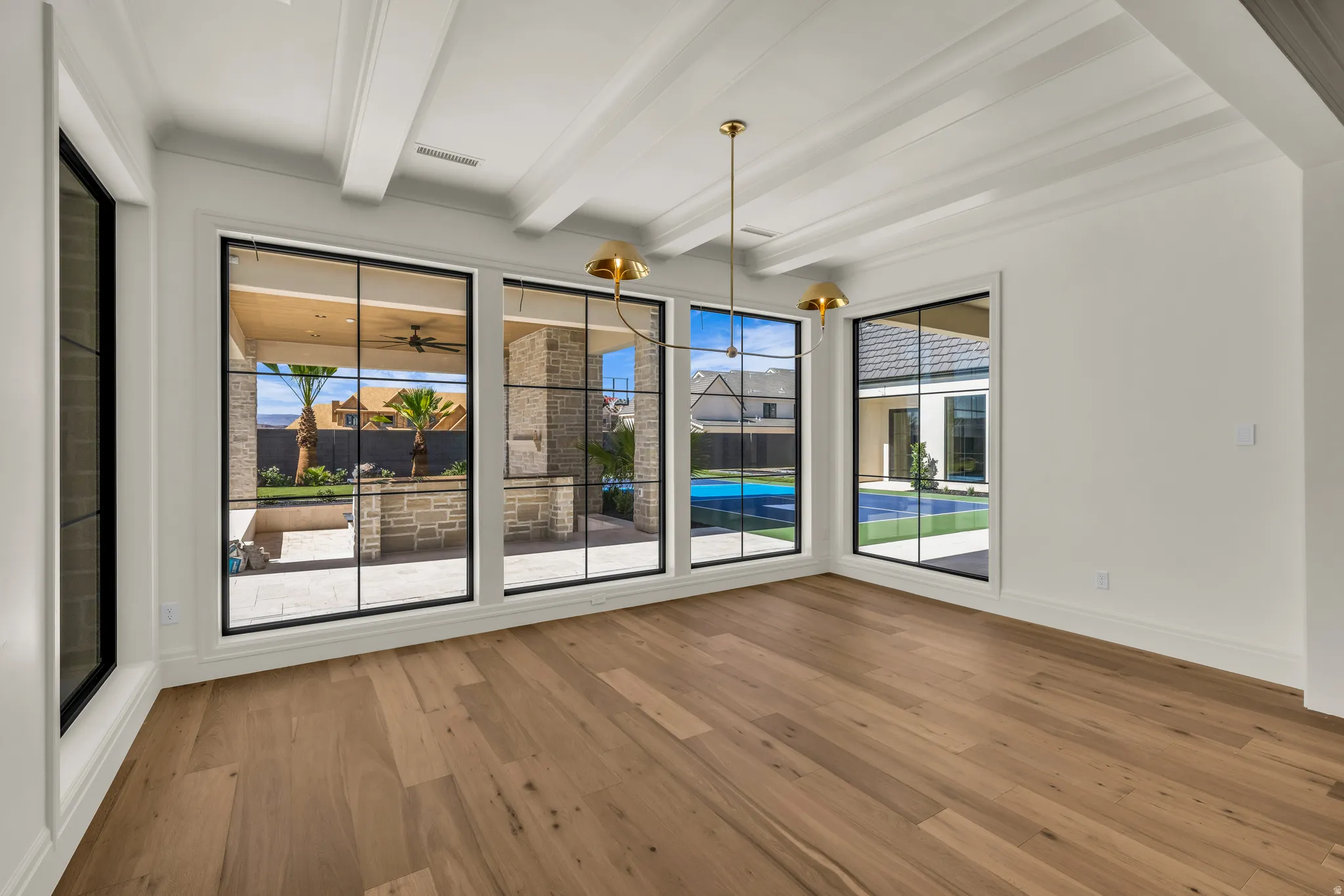 Interior space featuring wide plank wood-finish flooring, a coffered ceiling, and large windows with black framing