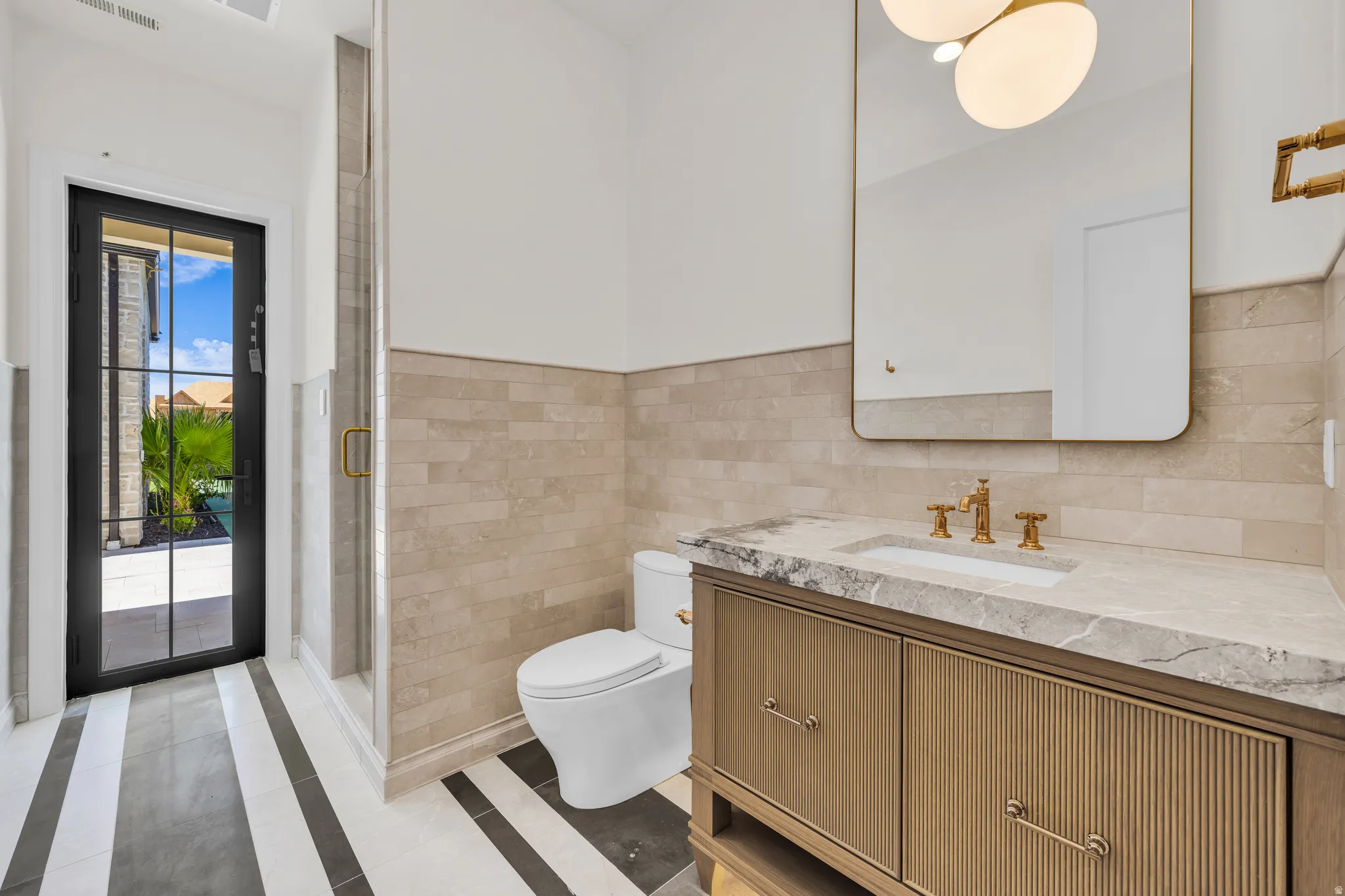 Bathroom featuring a glass-enclosed shower, a modern vanity with a stone countertop, and a black-framed glass door
