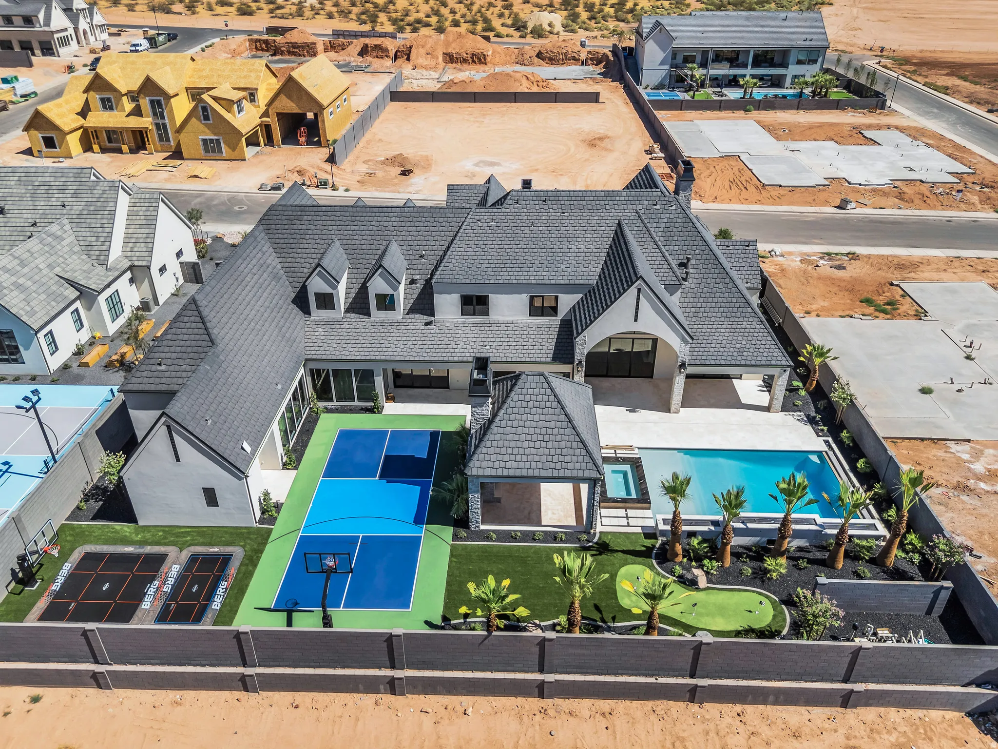 Rear exterior featuring a sport court, putting green, two in-ground trampolines, swimming pool with integrated spa, and an outdoor covered patio